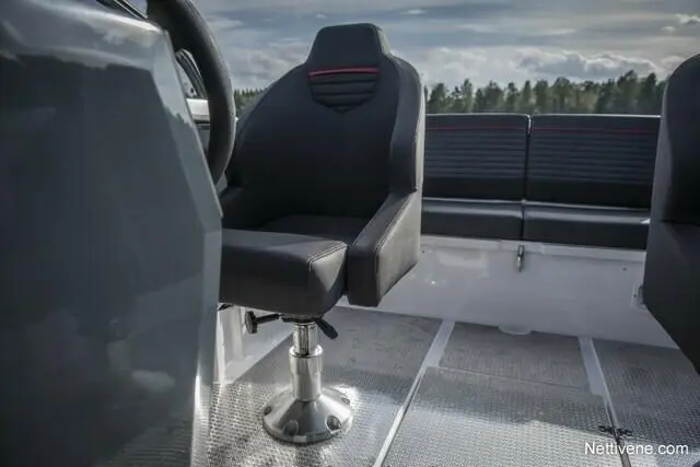 Black ergonomic boat seat positioned on a metallic deck, with a scenic background of trees and sky.
